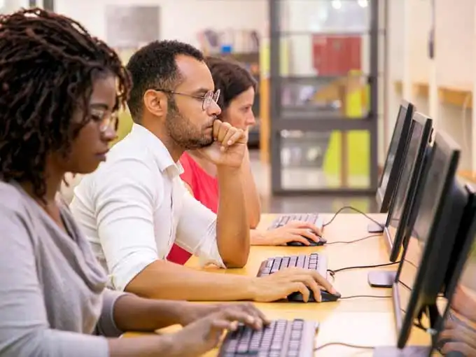 3 college students take exam at computers